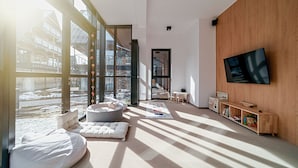 A modern living room with large windows, a flat-screen TV, and a cozy seating area. - Lipowy Dwór (Zakopane)