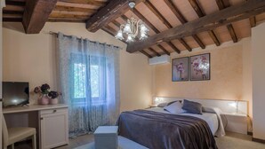 A bedroom with a bed, bedside tables, a desk, a chair, and a television. - Casale Andrea - 7 bedrooms, pool, airco, wifi, pet friendly, Umbria (Spoleto)