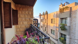 Un balcon doté de murs en pierre, d’un plafond en bois et offrant une vue sur les bâtiments adjacents.