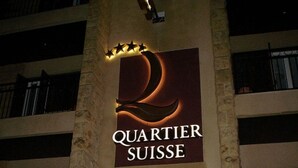 Un bâtiment portant une enseigne indiquant « Quartier Suisse » et « Restaurant », ce qui signifie qu’il s’agit d’un établissement où l’on peut prendre un repas.