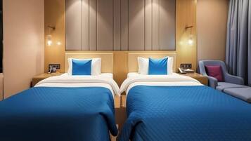 A hotel room with two beds, a chair, and a nightstand with a lamp.