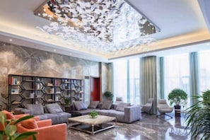 A modern living room with a marble floor, a sectional sofa, a coffee table, and a bookshelf. - Kaibin International Hotel (Xining)