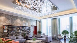 A spacious living area with a modern sofa set, a coffee table, and a decorative bookshelf. - Kaibin International Hotel (Xining)