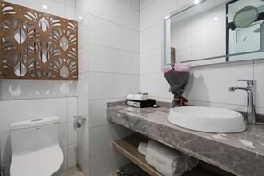 A modern bathroom with a toilet, a sink, a mirror, and a decorative panel. - Kaibin International Hotel (Xining)