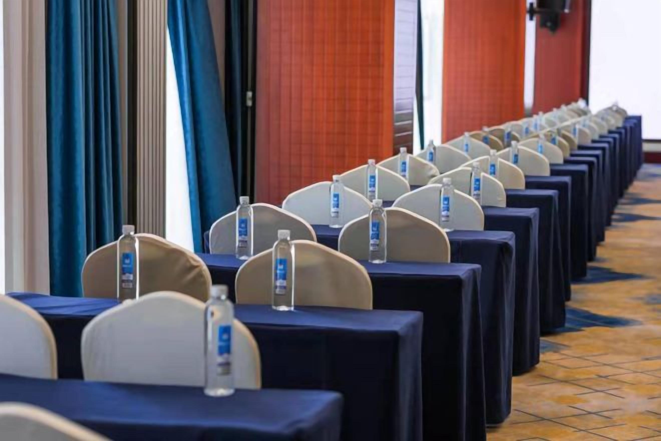 Rows of tables with water bottles, chairs, and name tags, indicating a conference or meeting setup.