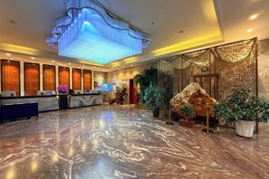 A hotel lobby with a marble floor, a reception desk, and a large decorative light fixture. - Kaibin International Hotel (Xining)