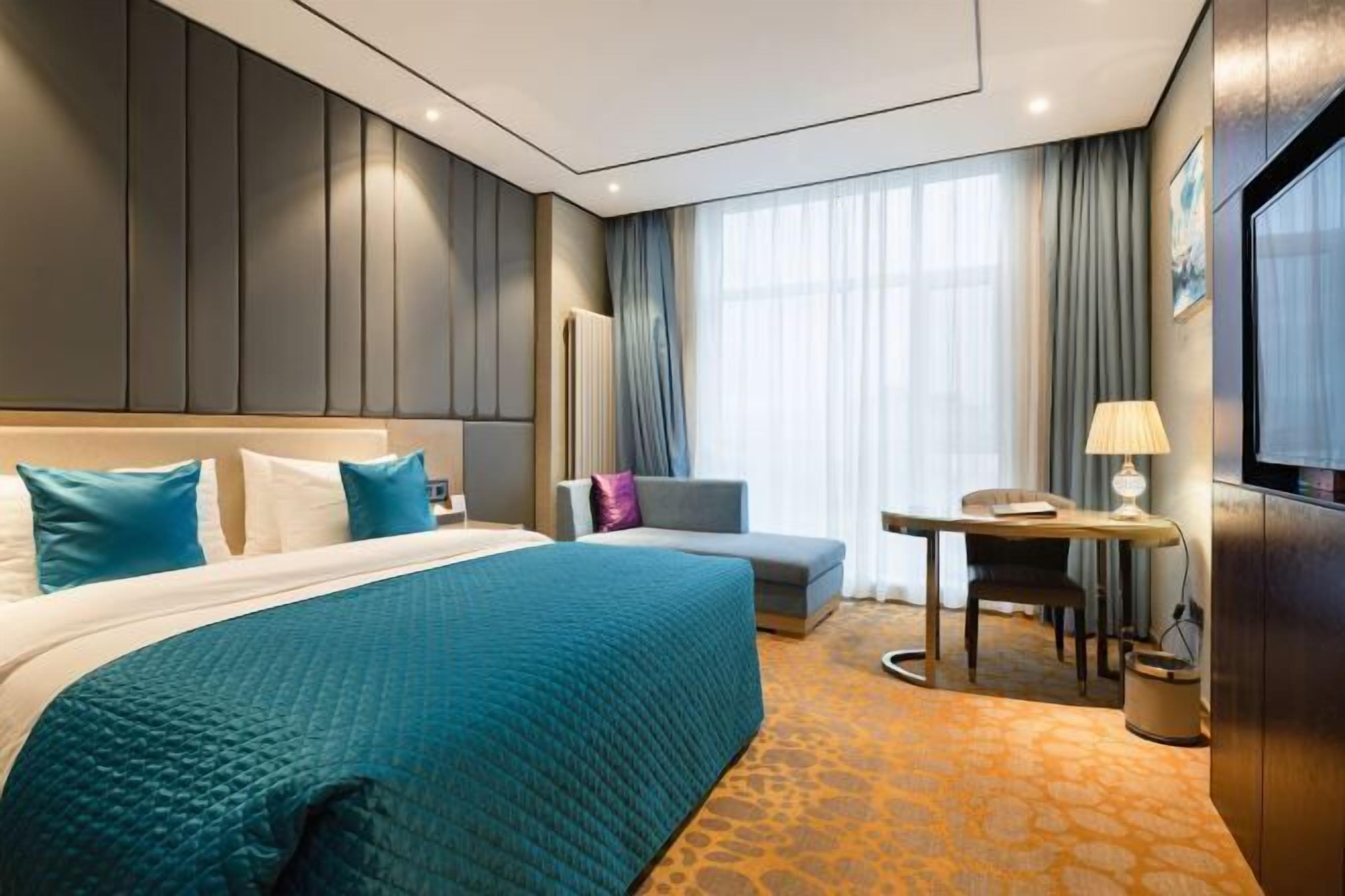 Una habitación de hotel con cama, escritorio, silla, sofá y televisión.
