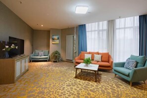 Ein Wohnzimmer mit einer Sofagarnitur, einem Couchtisch, einem Fernseher und einem gemusterten Teppich.