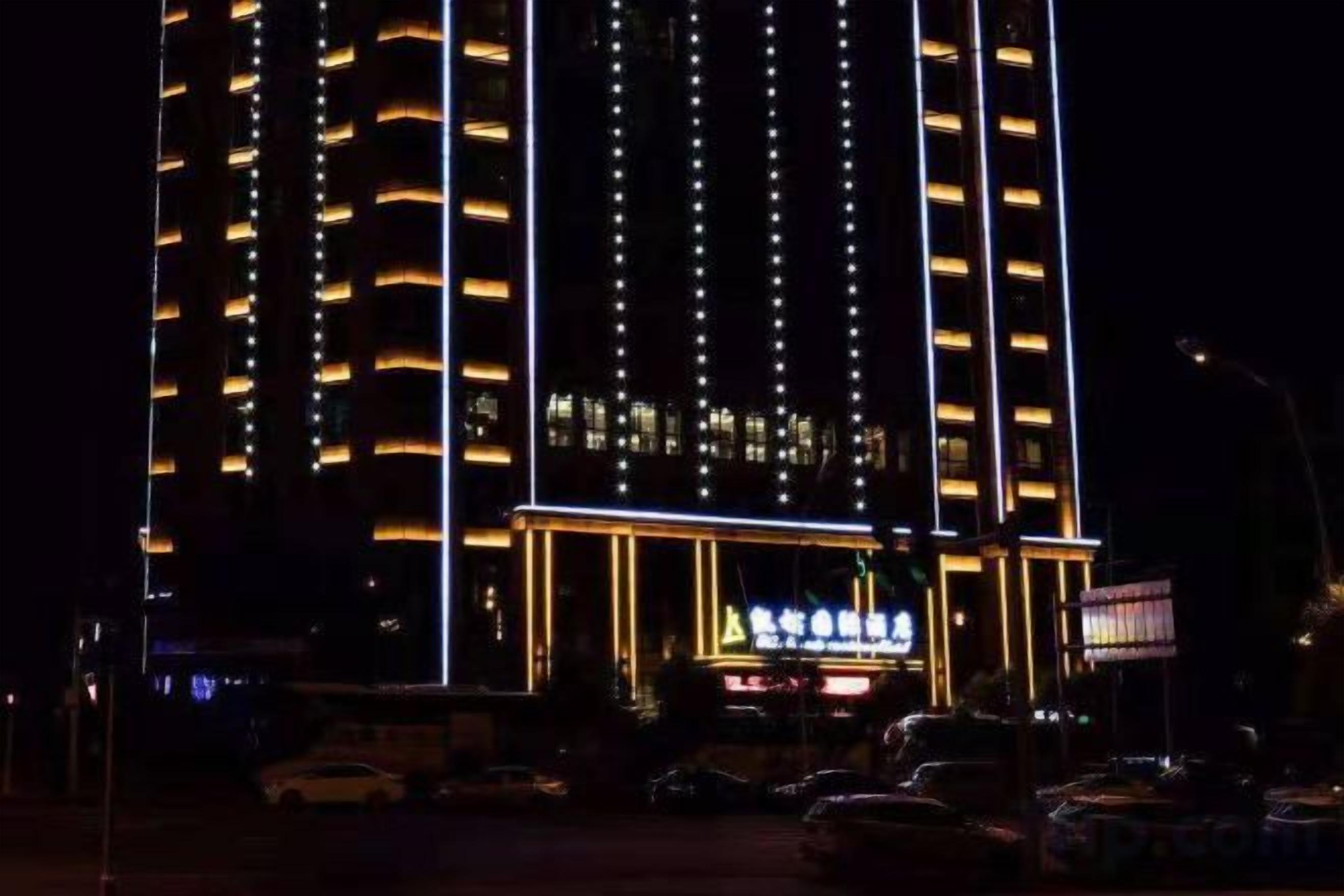 Un hotel a più piani con linee verticali illuminate e un ingresso illuminato.