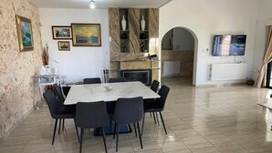 A dining area with a marble table and chairs, a fireplace, and a TV mounted on the wall.