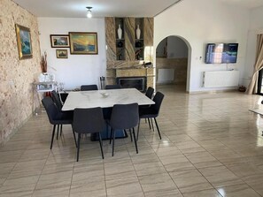 Un coin repas avec une table et des chaises en marbre, une cheminée et un téléviseur fixé au mur.