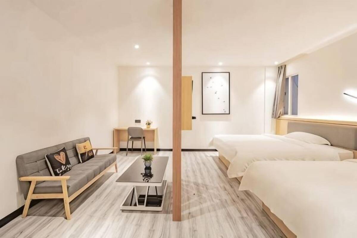 A hotel room with a bed, a sofa, a desk, and a chair.