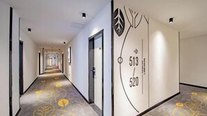 A hotel corridor with a modern design, featuring a carpet with leaf patterns and a wall with room numbers 513 and 520. - Changee Hotel (Haikou Qilou Old Street Nanya Plaza) (Haikou)