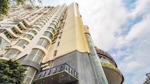 A high-rise hotel with a curved facade, multiple balconies, and a prominent entrance with signage. - Changee Hotel (Haikou Qilou Old Street Nanya Plaza) (Haikou)