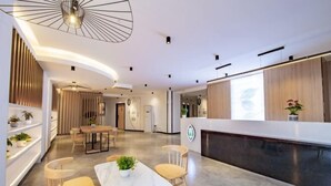 A modern hotel lobby with a reception desk, seating area, and a plant display. - Changee Hotel (Haikou Qilou Old Street Nanya Plaza) (Haikou)