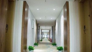 A long, narrow hallway with wooden doors on either side, leading to a bright, well-lit room at the end. - Jinghe Holiday Hotel (Wuhan)