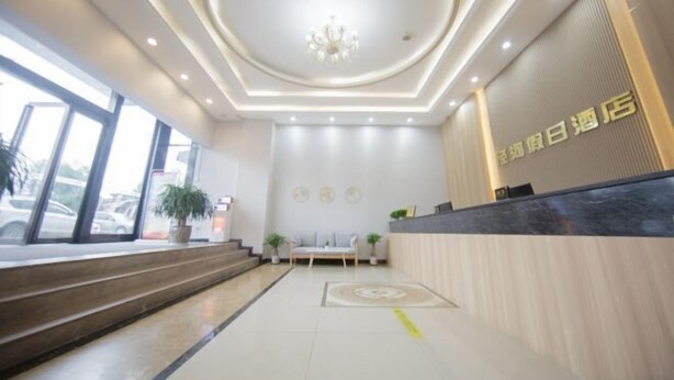 A hotel reception area with a modern design, featuring a reception desk, seating area, and a chandelier. - Jinghe Holiday Hotel (Wuhan)