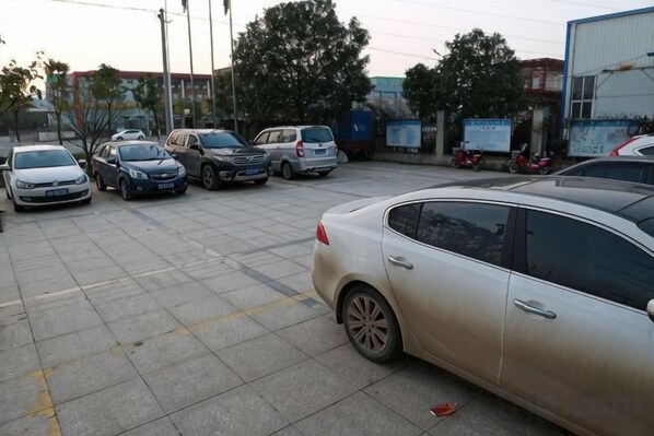 A parking lot with several cars parked, including a silver sedan and a white car. - Jinghe Holiday Hotel (Wuhan)