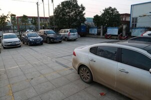 Un estacionamiento con varios autos estacionados, incluyendo un sedán plateado y un auto blanco.