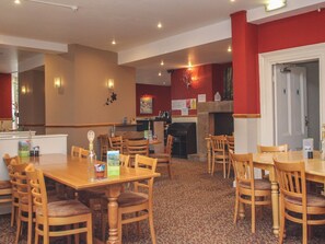 A restaurant with wooden tables and chairs, a counter, and a fireplace. - Valley Lodge 33 (Gunnislake)