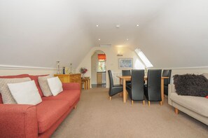 A cozy living room with a red sofa, a beige sofa, and a dining area with a table and chairs. - Valley Lodge 33 (Gunnislake)