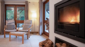 Un salon chaleureux avec deux fauteuils à motifs, une cheminée et un téléviseur.