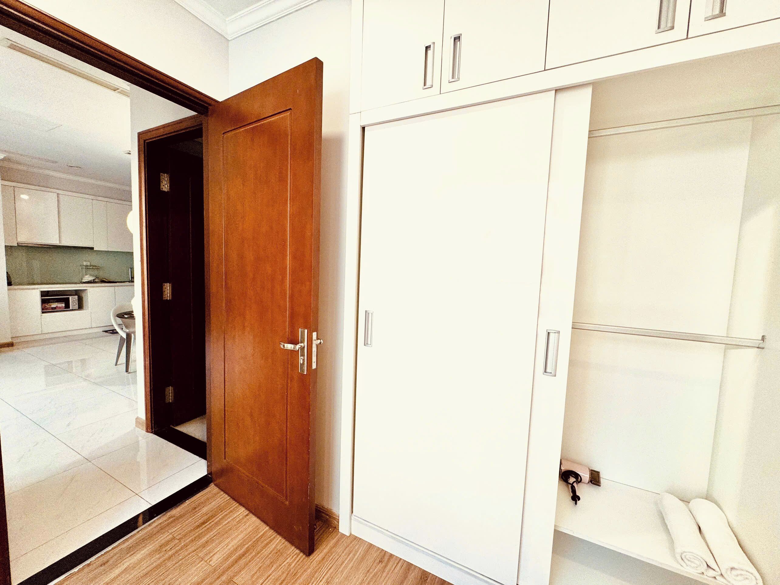 Ein Zimmer mit Holztür, weißem Kleiderschrank und einer kleinen Sitzecke mit Handtuch.