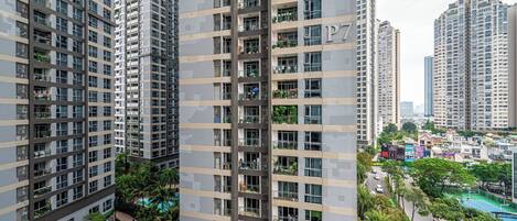 Un immeuble résidentiel de grande hauteur doté de nombreux balcons, d’une piscine et entouré d’un quartier urbain comprenant d’autres immeubles de grande hauteur.