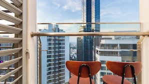 Een balkon met twee stoelen en uitzicht op hoge gebouwen.