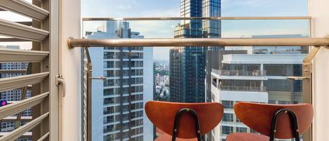 A balcony with two chairs and a view of tall buildings.