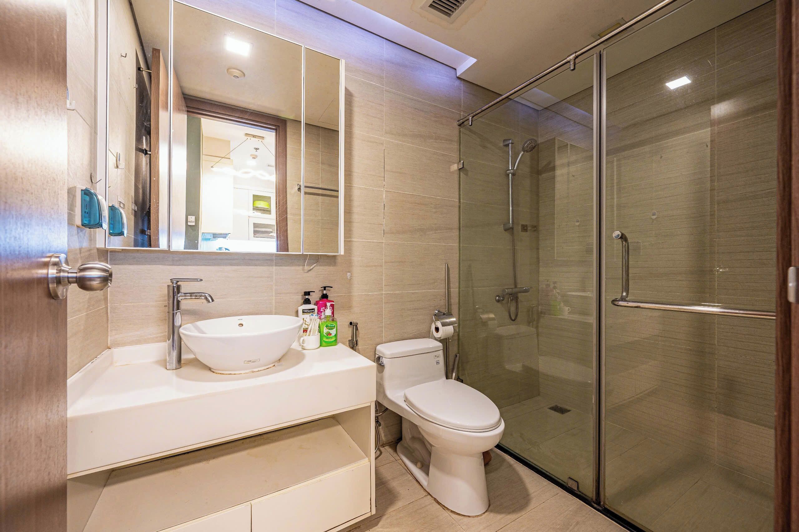 A modern bathroom with a glass-enclosed shower, a white sink, and a toilet.