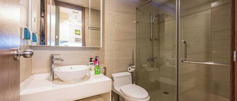 A modern bathroom with a glass-enclosed shower, a white sink, and a toilet.