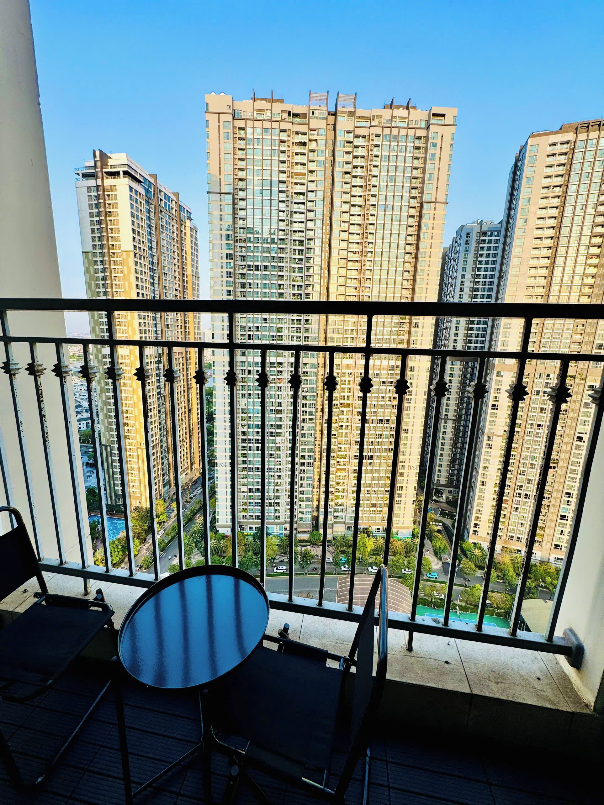 Un balcón con mesa y sillas, con vistas a un paisaje urbano con rascacielos.