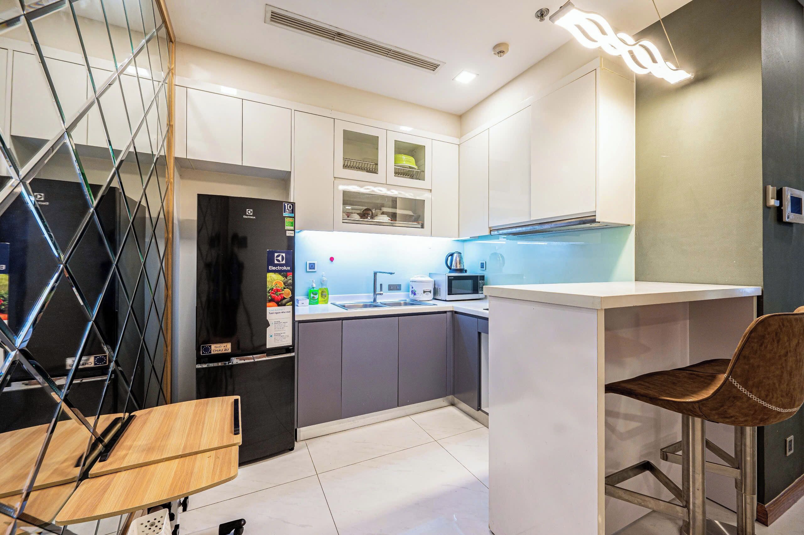 Una cucina moderna con forno a microonde, lavello e un piccolo angolo ristoro con una sedia.