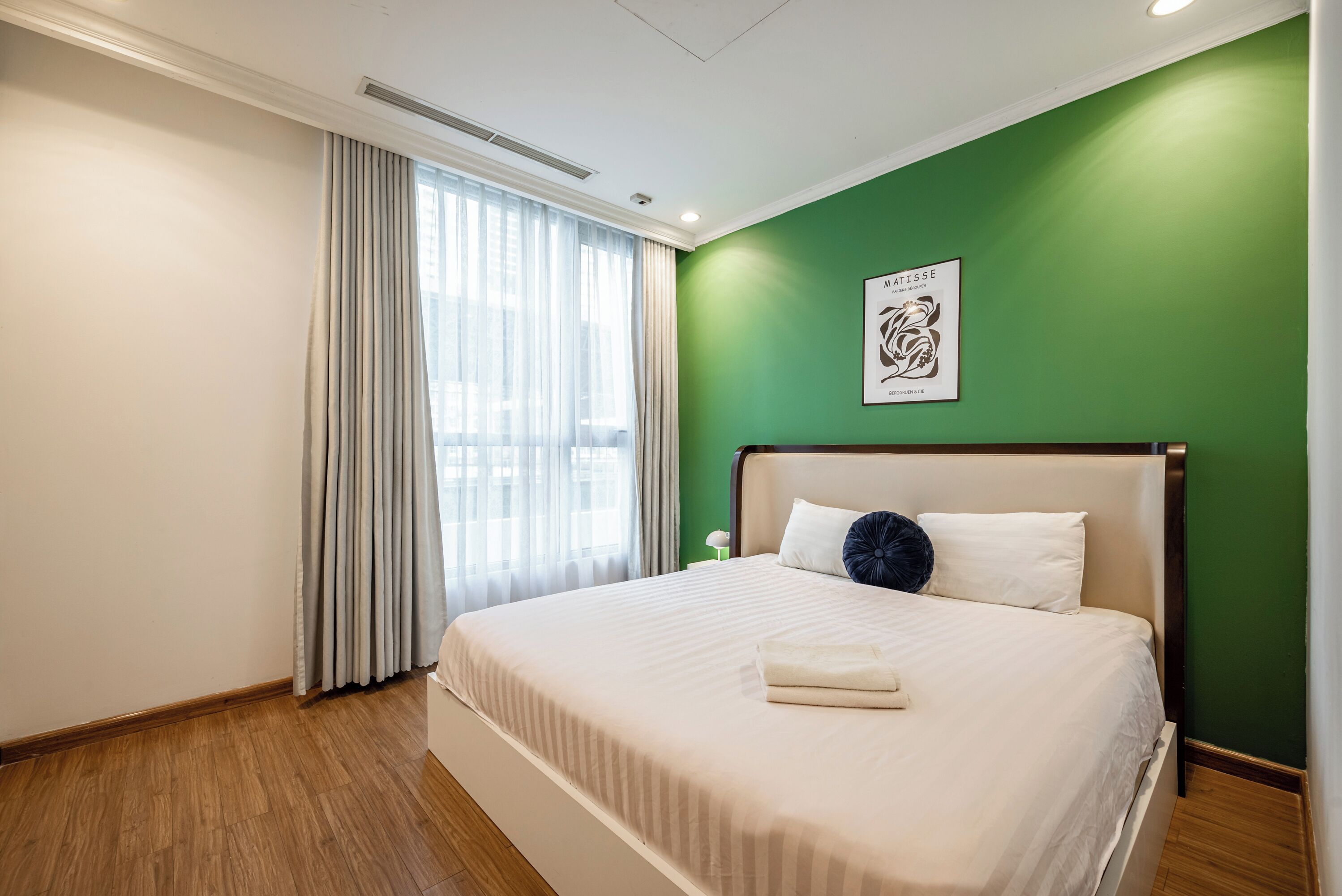 Ein Hotelzimmer mit einem großen Bett, grünen Wänden und einem Fenster mit Vorhängen.