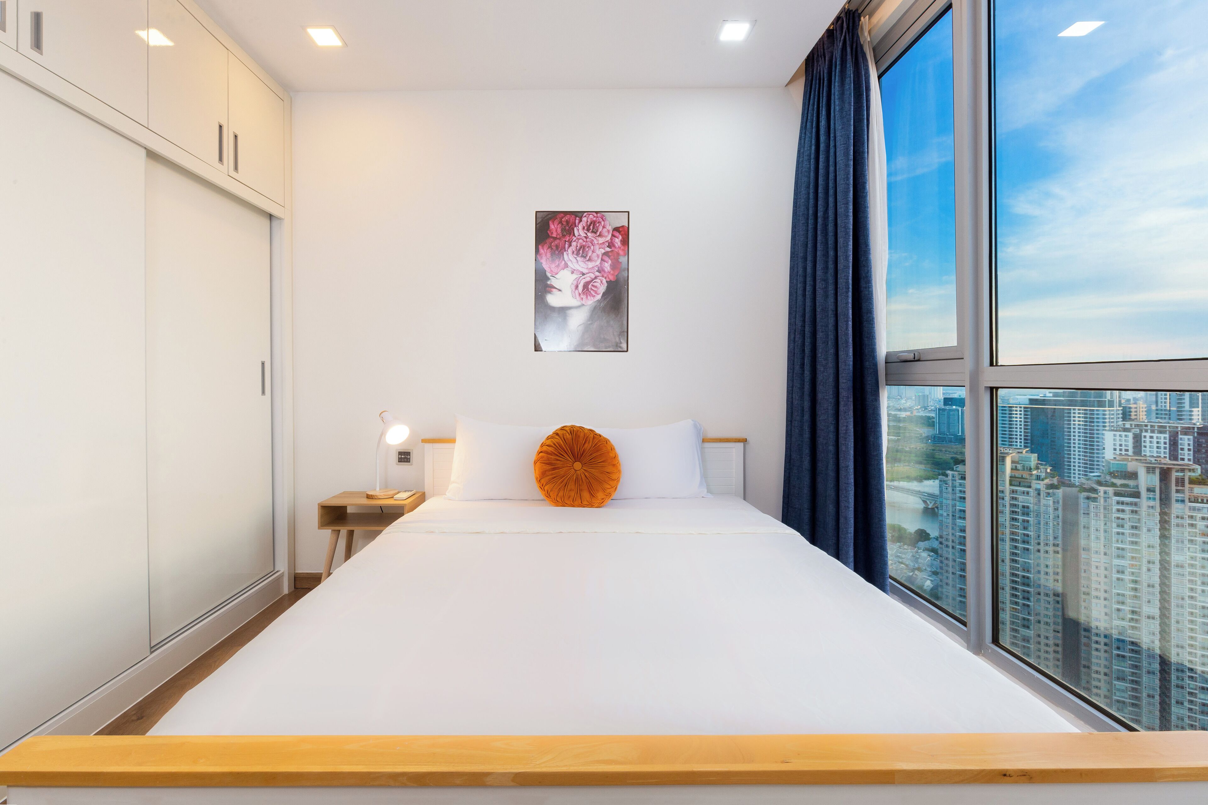 Ein modernes Hotelzimmer mit einem großen Bett, Blick auf die Stadt und einem Gemälde an der Wand.