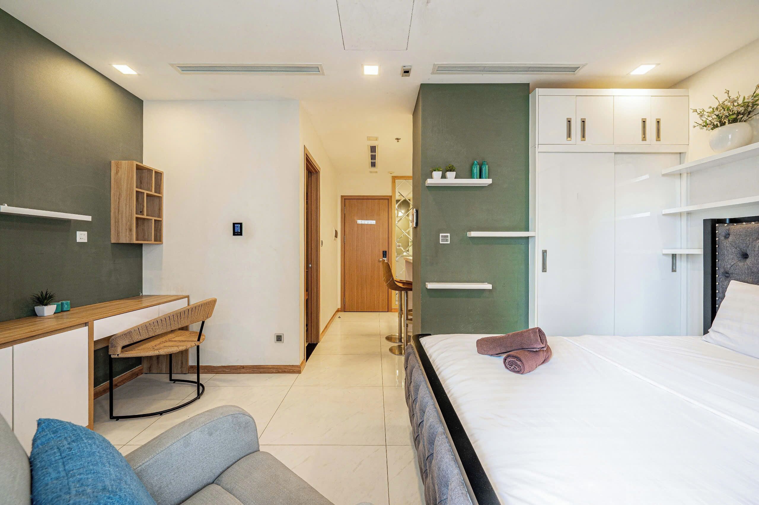 A modern hotel room with a bed, a desk, and a seating area.