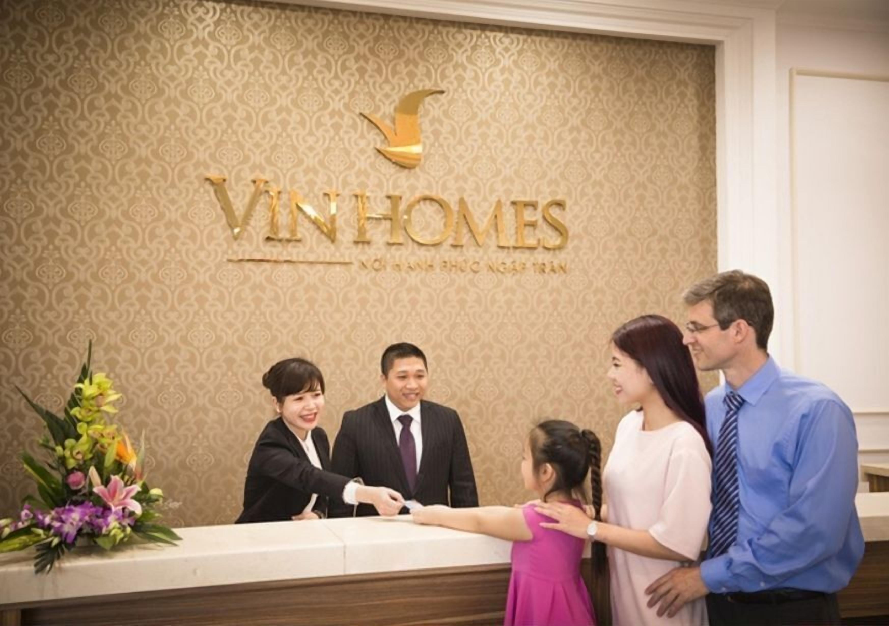 A reception desk with a logo and a floral arrangement.