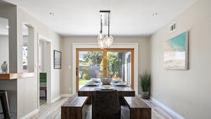Un espace repas avec une table en bois, des bancs et un lustre.