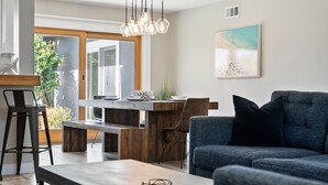 Un salon moderne avec un canapé bleu, une table basse en bois et un coin repas comprenant une table et des chaises en bois.