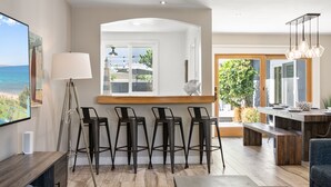 Une cuisine moderne dotée d’un îlot central, de tabourets de bar et offrant une vue sur l’océan.