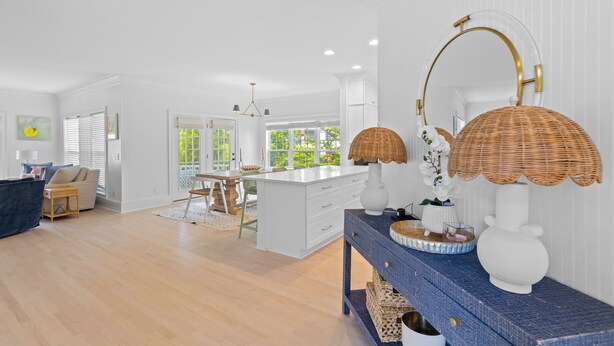 A spacious living area with a large island, a dining table, and a blue console table with decorative items. - 3 Summer Dunes - Renovated Ocean View Beach House! (Isle of Palms)