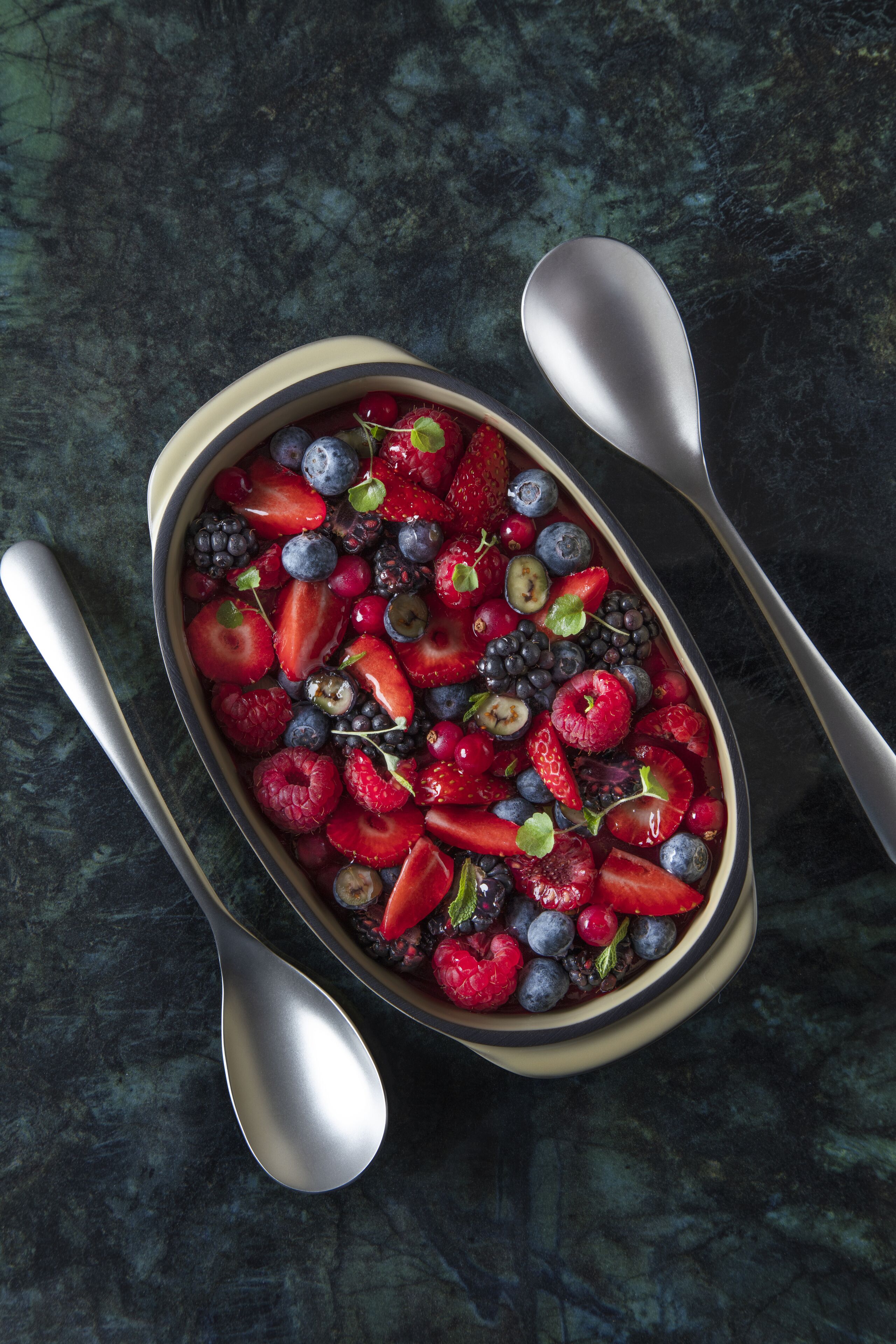 Un bol de fruits rouges mélangés et une cuillère.