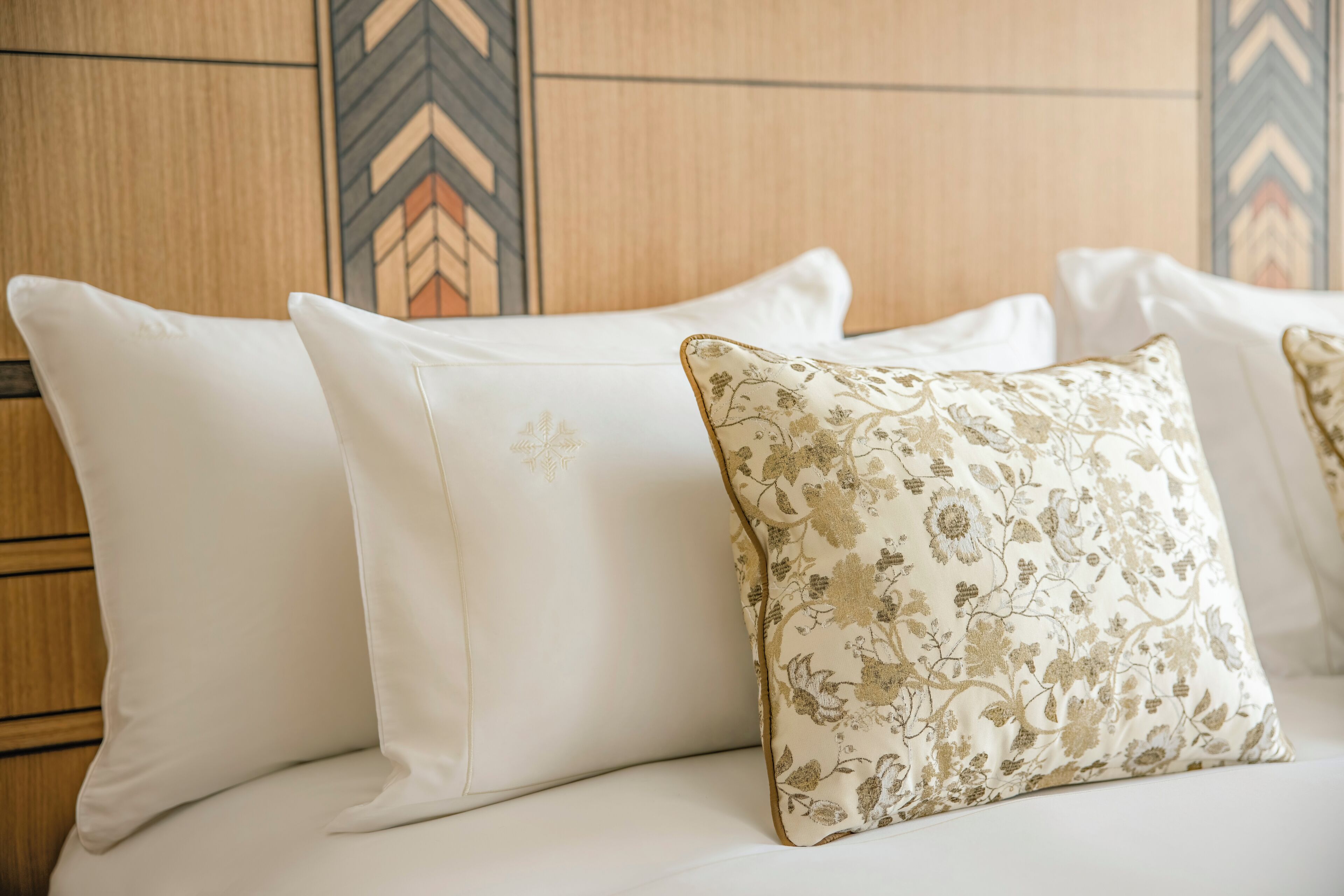 A bed with white pillows and one with a floral pattern.