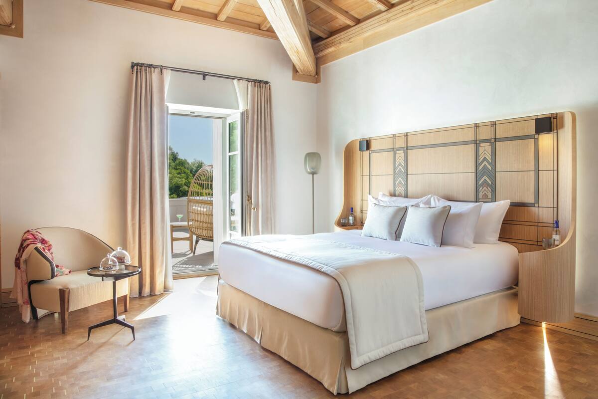 Une chambre spacieuse avec un grand lit, une petite table avec une théière et une chaise.
