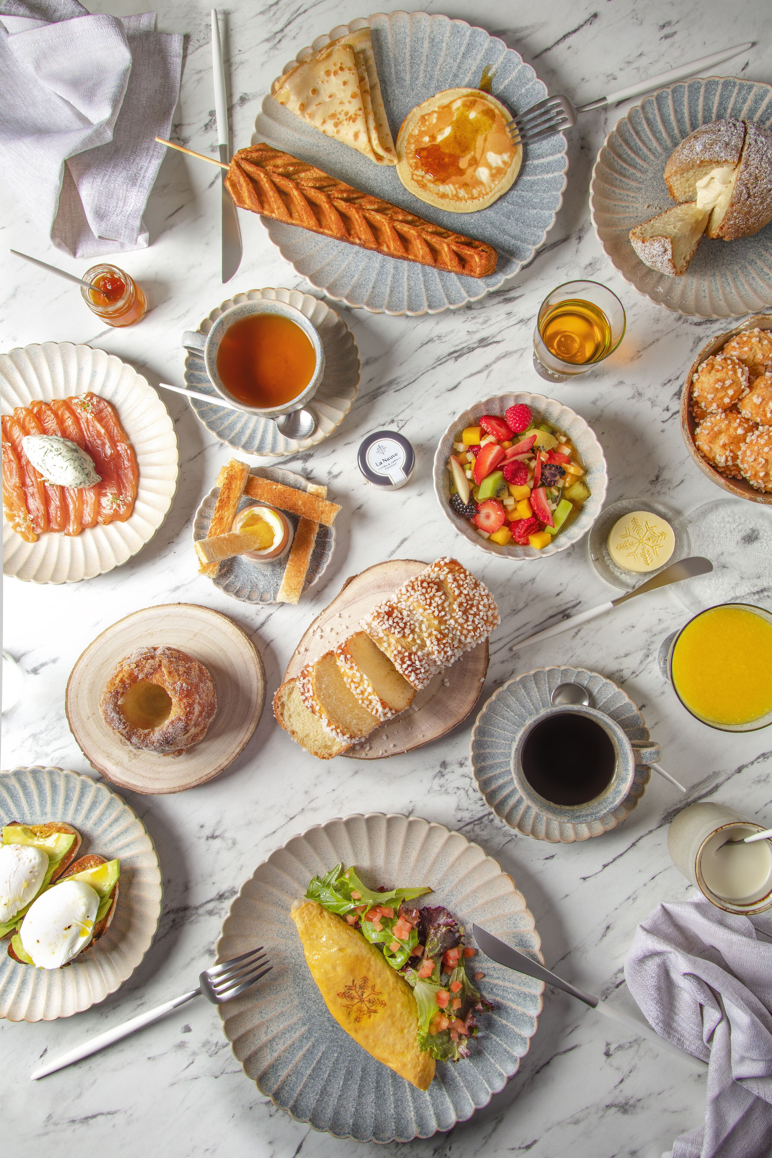 A variety of breakfast dishes on plates, including pancakes, pastries, and a salad.
