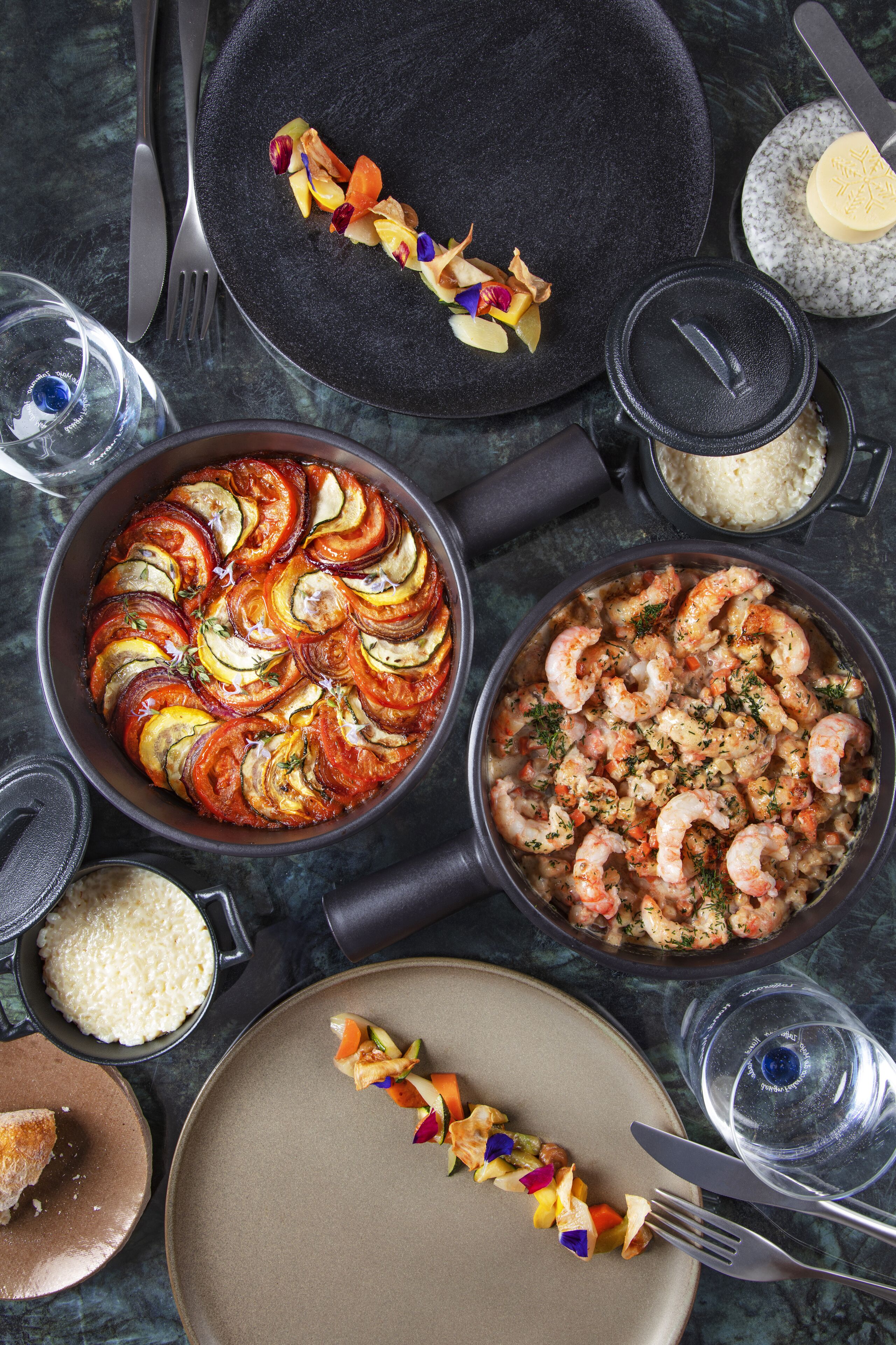 Une table à manger avec différents plats, notamment une tarte, des crevettes et un assortiment de fruits.