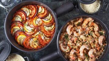 Une table à manger avec différents plats, notamment une tarte, des crevettes et un assortiment de fruits.