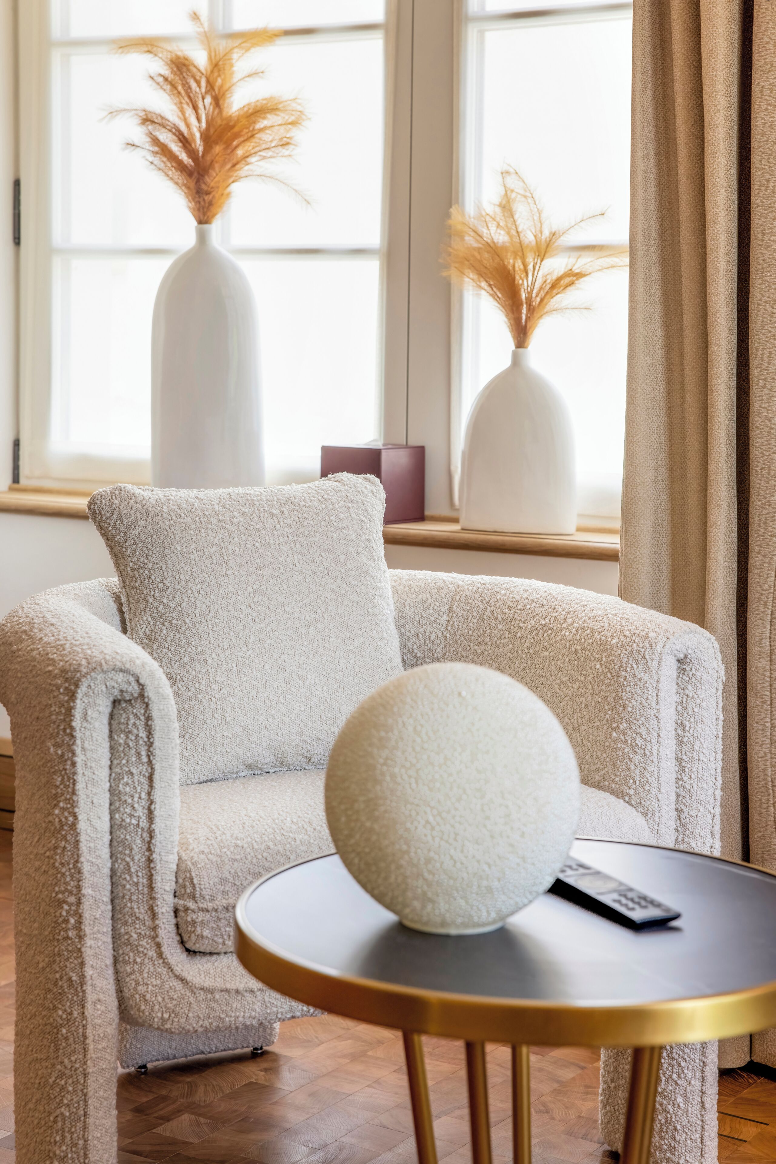 Une pièce chaleureuse avec un canapé moelleux, un petit pouf rond blanc et une petite table sur laquelle se trouve une télécommande.
