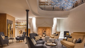 Een ruime lobby met modern meubilair, een statige trap en een decoratieve kroonluchter.
